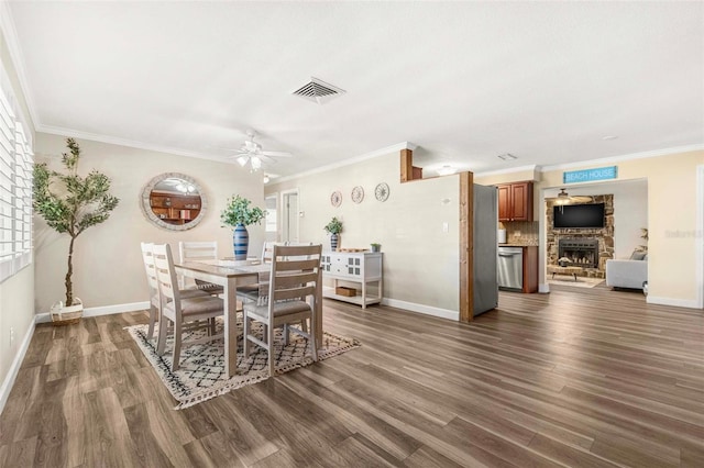 10339 111th St, Largo, FL 33778 - dining room featuring ceiling fan, dark wood-style flooring, ornamental molding, and a stone fireplace