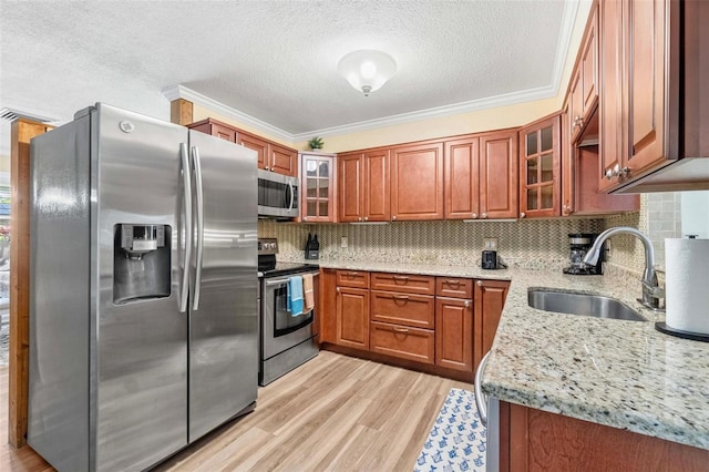 10339 111th St, Largo, FL 33778 - kitchen featuring appliances with stainless steel finishes, light stone counters, brown cabinets, light wood-style floors, and tasteful backsplash