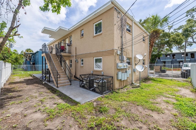 1771 Russell St S, Saint Petersburg, FL 33712 - back of property featuring stucco siding, a fenced backyard, stairway, and a patio