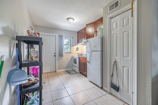1771 Russell St S, Saint Petersburg, FL 33712 - kitchen with white appliances, under cabinet range hood, brown cabinets, and light tile patterned flooring