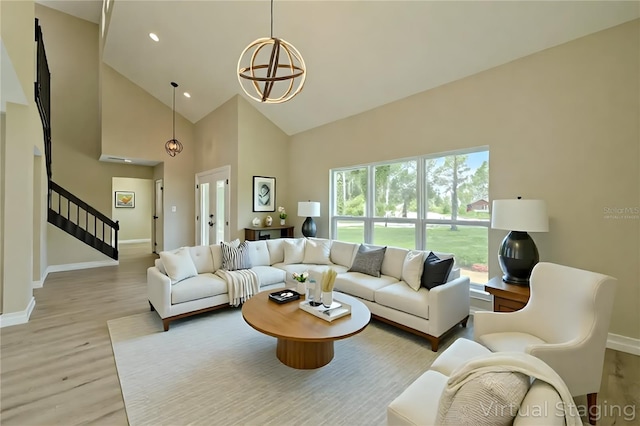 4044 Red Fox Ct, Wesley Chapel, FL 33543 - living room featuring high vaulted ceiling, stairs, baseboards, light wood-type flooring, and a chandelier