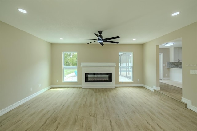 4044 Red Fox Ct, Wesley Chapel, FL 33543 - unfurnished living room with light wood-type flooring, baseboards, a glass covered fireplace, ceiling fan, and recessed lighting