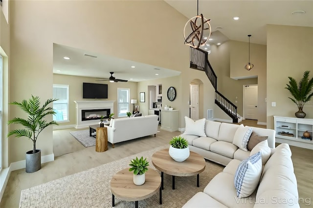 4044 Red Fox Ct, Wesley Chapel, FL 33543 - living room with arched walkways, a ceiling fan, high vaulted ceiling, baseboards, and a glass covered fireplace