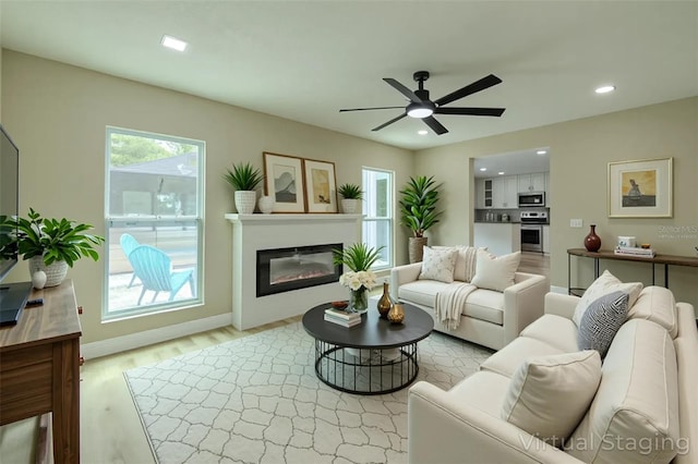 4044 Red Fox Ct, Wesley Chapel, FL 33543 - living area with recessed lighting, light wood-type flooring, a ceiling fan, a glass covered fireplace, and baseboards