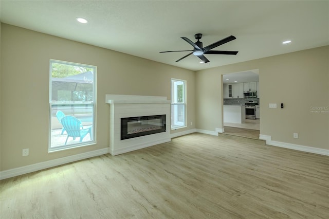 4044 Red Fox Ct, Wesley Chapel, FL 33543 - unfurnished living room with light wood-type flooring, a glass covered fireplace, baseboards, recessed lighting, and a ceiling fan
