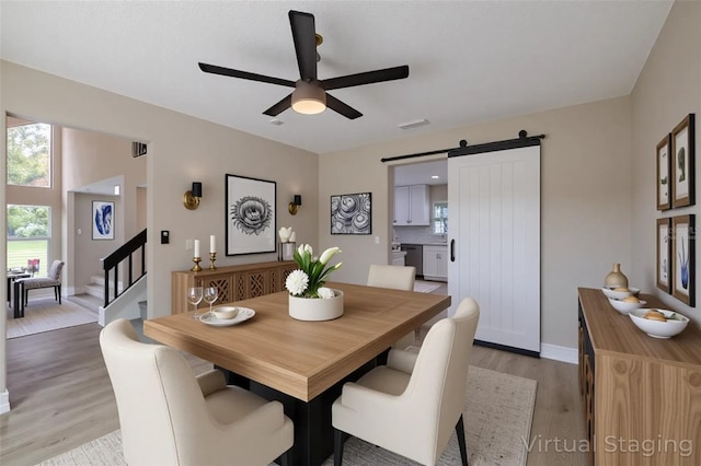 4044 Red Fox Ct, Wesley Chapel, FL 33543 - dining space featuring a ceiling fan, light wood-style floors, a barn door, stairway, and baseboards