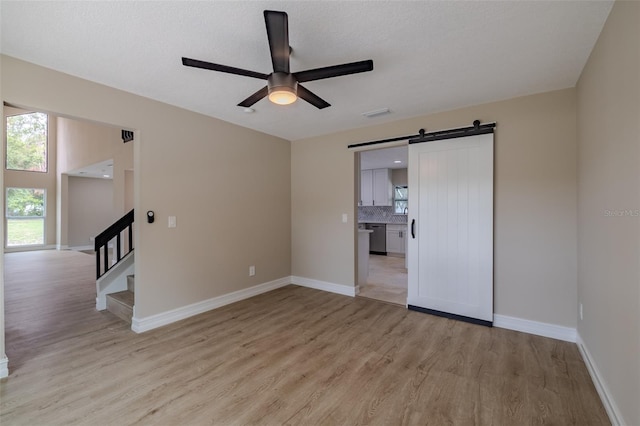 4044 Red Fox Ct, Wesley Chapel, FL 33543 - spare room with light wood finished floors, a ceiling fan, a barn door, and stairway