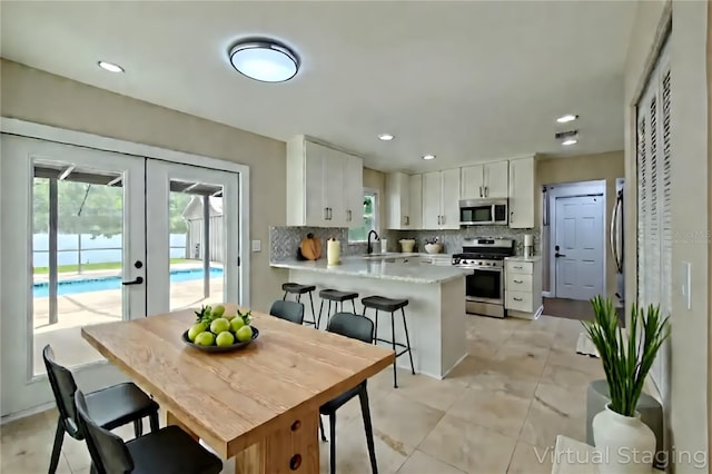 4044 Red Fox Ct, Wesley Chapel, FL 33543 - kitchen with appliances with stainless steel finishes, french doors, a peninsula, backsplash, and white cabinets