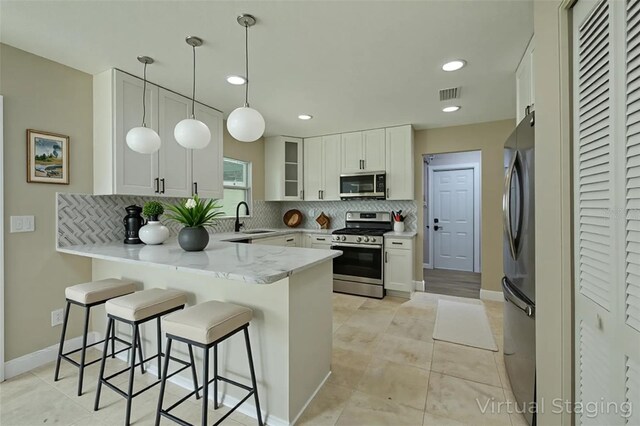 4044 Red Fox Ct, Wesley Chapel, FL 33543 - kitchen with stainless steel appliances, a peninsula, tasteful backsplash, a kitchen bar, and recessed lighting