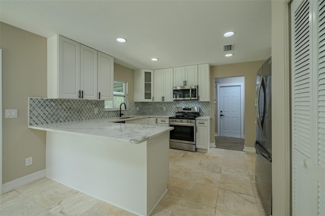4044 Red Fox Ct, Wesley Chapel, FL 33543 - kitchen with stainless steel appliances, a peninsula, a sink, tasteful backsplash, and white cabinetry