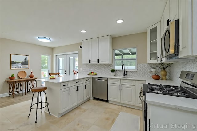 4044 Red Fox Ct, Wesley Chapel, FL 33543 - kitchen featuring stainless steel appliances, a sink, a peninsula, decorative backsplash, and white cabinetry