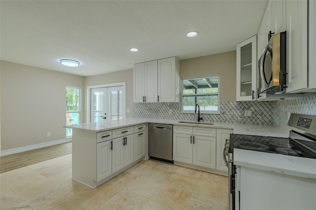 4044 Red Fox Ct, Wesley Chapel, FL 33543 - kitchen with appliances with stainless steel finishes, a sink, a peninsula, decorative backsplash, and glass insert cabinets