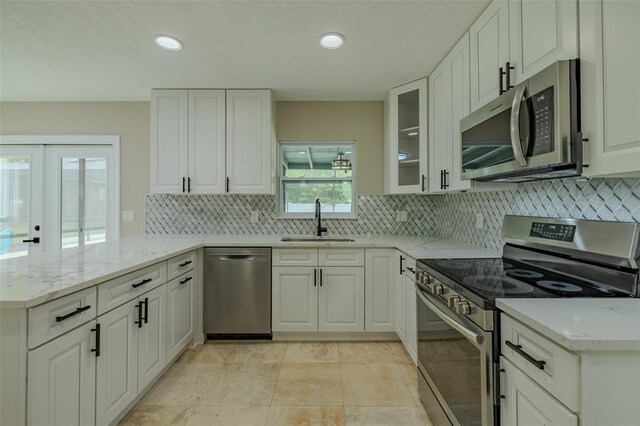 4044 Red Fox Ct, Wesley Chapel, FL 33543 - kitchen featuring appliances with stainless steel finishes, a sink, a peninsula, backsplash, and white cabinetry