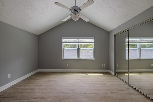 4044 Red Fox Ct, Wesley Chapel, FL 33543 - unfurnished bedroom with a textured ceiling, wood finished floors, a closet, vaulted ceiling, and baseboards