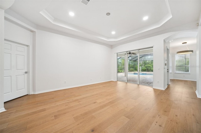 17802 Mission Oak Dr, Lithia, FL 33547 - empty room featuring a tray ceiling, light wood-style floors, arched walkways, crown molding, and recessed lighting