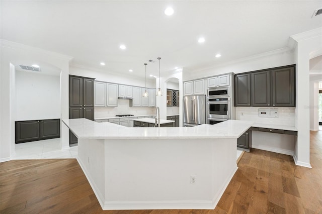 17802 Mission Oak Dr, Lithia, FL 33547 - kitchen featuring appliances with stainless steel finishes, a spacious island, arched walkways, decorative backsplash, and crown molding