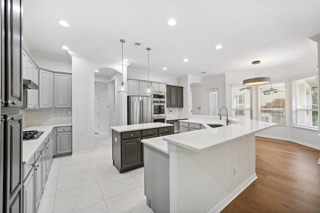 17802 Mission Oak Dr, Lithia, FL 33547 - kitchen with a large island, stainless steel appliances, gray cabinets, arched walkways, and ornamental molding