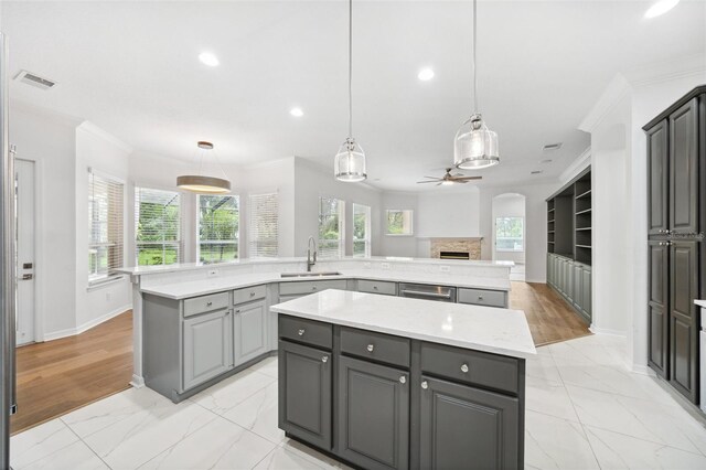 17802 Mission Oak Dr, Lithia, FL 33547 - kitchen with a sink, a center island, gray cabinetry, light marble finish floors, and ornamental molding