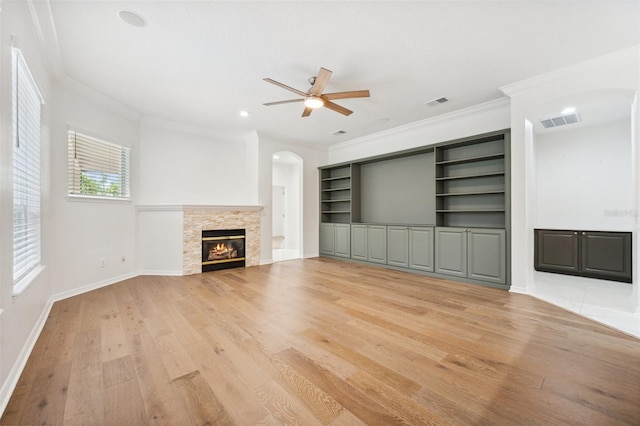 17802 Mission Oak Dr, Lithia, FL 33547 - unfurnished living room with arched walkways, ceiling fan, light wood-type flooring, ornamental molding, and a fireplace