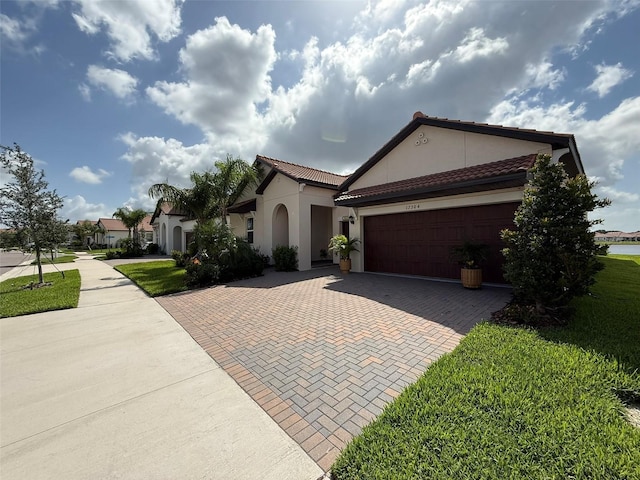 17304 Scuba Crest St, Wimauma, FL 33598 - mediterranean / spanish-style home with decorative driveway, stucco siding, a garage, a tile roof, and a front yard