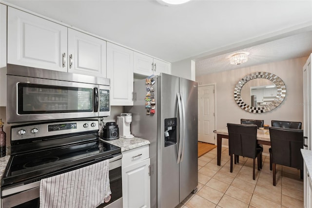 11809 Raintree Lake Ln Unit A, Tampa, FL 33617 - kitchen featuring appliances with stainless steel finishes, white cabinetry, light tile patterned floors, and light stone counters