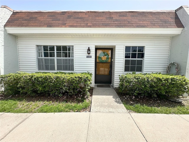 13926 Mission Oaks Blvd, Seminole, FL 33776 - view of exterior entry featuring a shingled roof and mansard roof