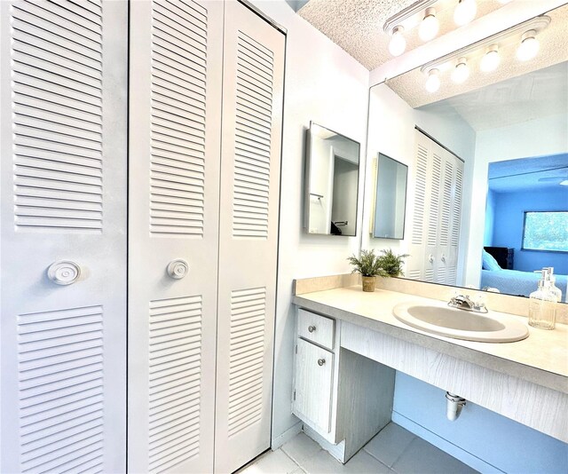 13926 Mission Oaks Blvd, Seminole, FL 33776 - ensuite bathroom featuring a closet, vanity, tile patterned flooring, and a textured ceiling