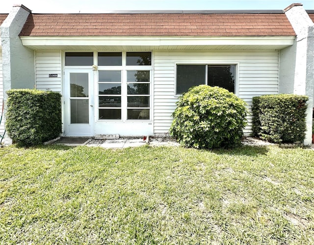 13926 Mission Oaks Blvd, Seminole, FL 33776 - entrance to property featuring a shingled roof, a lawn, and mansard roof