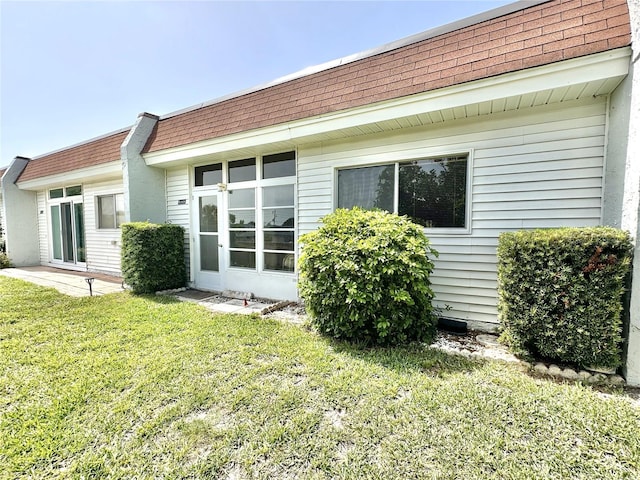 13926 Mission Oaks Blvd, Seminole, FL 33776 - back of property with roof with shingles, mansard roof, and a lawn