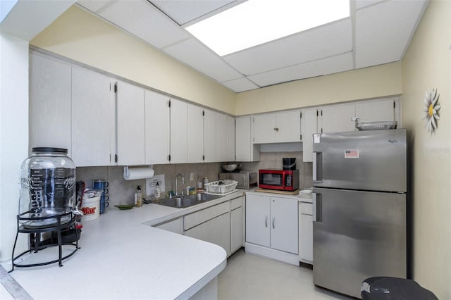 13926 Mission Oaks Blvd, Seminole, FL 33776 - kitchen with stainless steel appliances, a sink, backsplash, light countertops, and a peninsula