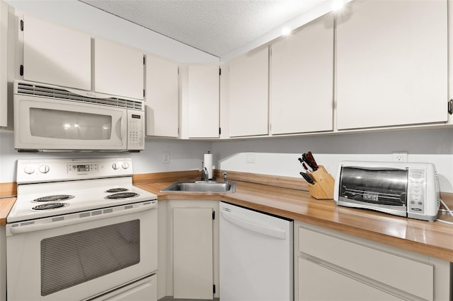 2699 Pine Ridge Way E Unit H2, Palm Harbor, FL 34684 - kitchen with white appliances, white cabinetry, and wood counters