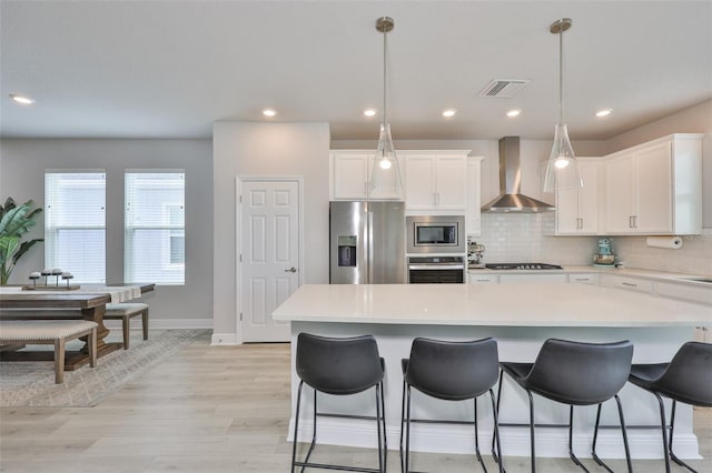 5511 Del Coronado Dr, Apollo Beach, FL 33572 - kitchen with stainless steel appliances, wall chimney exhaust hood, a center island, backsplash, and white cabinets