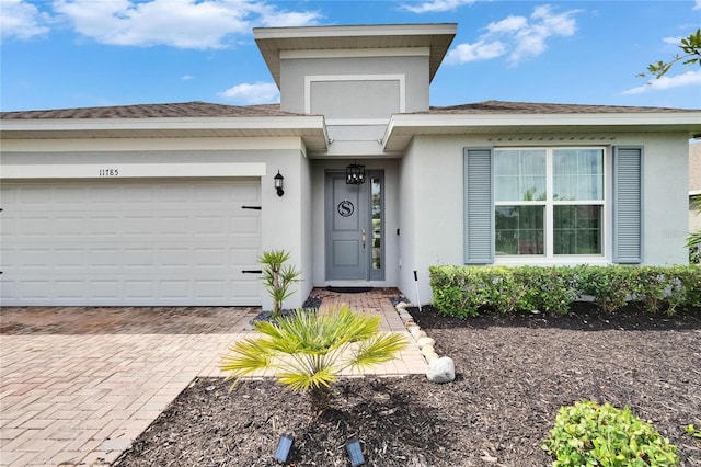 11785 Little River Way, Parrish, FL 34219 - doorway to property with stucco siding, decorative driveway, and a garage