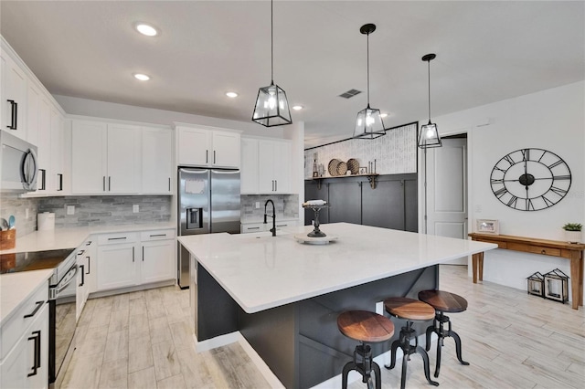 11785 Little River Way, Parrish, FL 34219 - kitchen featuring stainless steel appliances, backsplash, light wood finished floors, light countertops, and white cabinets
