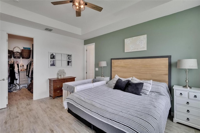 11785 Little River Way, Parrish, FL 34219 - bedroom with a spacious closet, light wood-style floors, a closet, a tray ceiling, and a ceiling fan