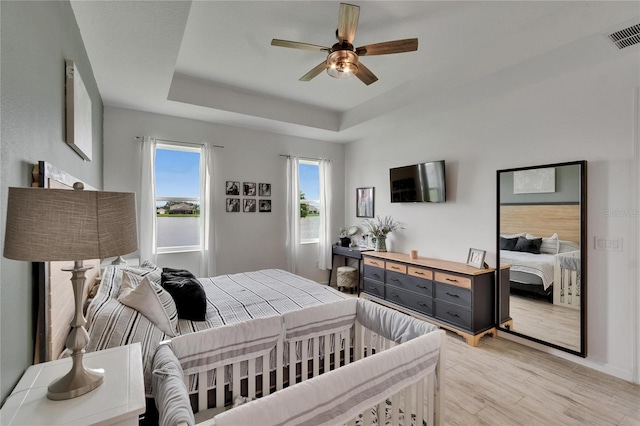 11785 Little River Way, Parrish, FL 34219 - bedroom featuring light wood-style flooring, a tray ceiling, a ceiling fan, and baseboards