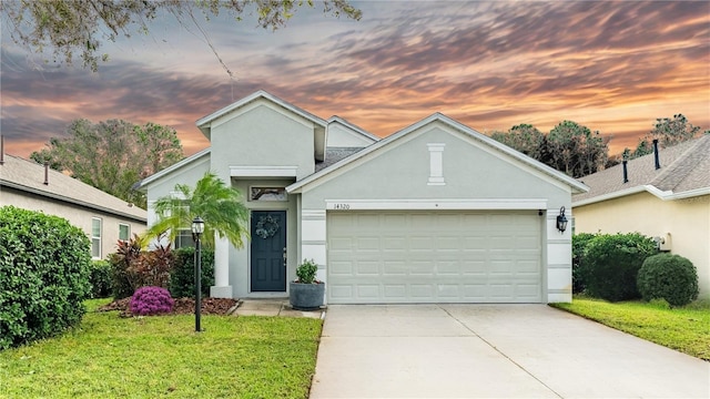 14320 Tree Swallow Way, Lakewood Ranch, FL 34202 - view of front of house featuring stucco siding, a lawn, an attached garage, and driveway