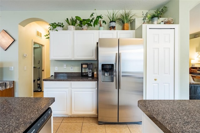 14320 Tree Swallow Way, Lakewood Ranch, FL 34202 - kitchen featuring stainless steel refrigerator with ice dispenser, arched walkways, white cabinetry, light tile patterned floors, and dark stone counters