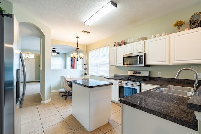 14320 Tree Swallow Way, Lakewood Ranch, FL 34202 - kitchen featuring appliances with stainless steel finishes, a sink, white cabinetry, dark countertops, and a textured ceiling