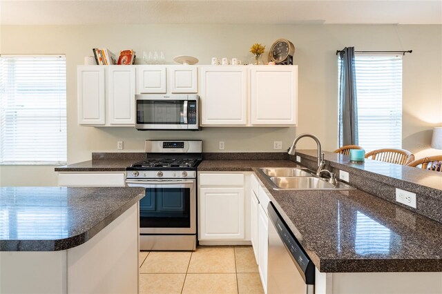 14320 Tree Swallow Way, Lakewood Ranch, FL 34202 - kitchen with appliances with stainless steel finishes, a sink, a peninsula, dark countertops, and light tile patterned floors