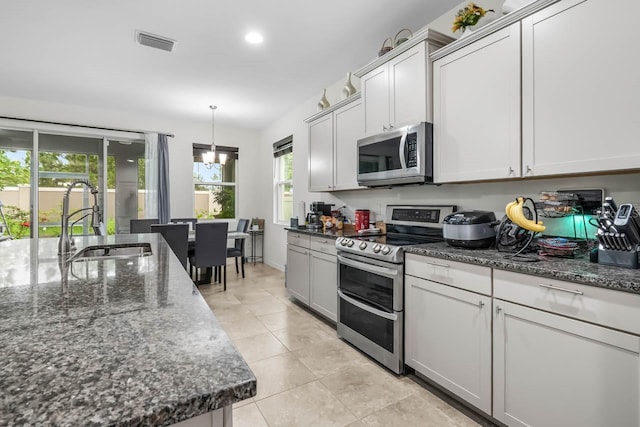 5006 Jackel Chase Dr, Wimauma, FL 33598 - kitchen featuring appliances with stainless steel finishes, a sink, light tile patterned floors, dark stone counters, and recessed lighting