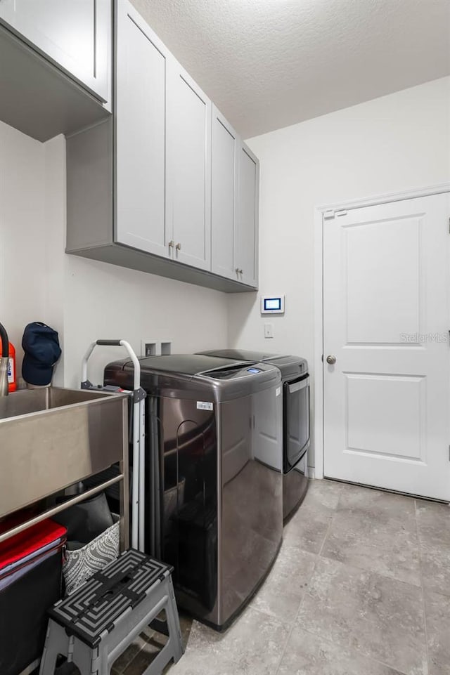 5006 Jackel Chase Dr, Wimauma, FL 33598 - laundry room featuring cabinet space, washing machine and dryer, light stone finish flooring, and a textured ceiling