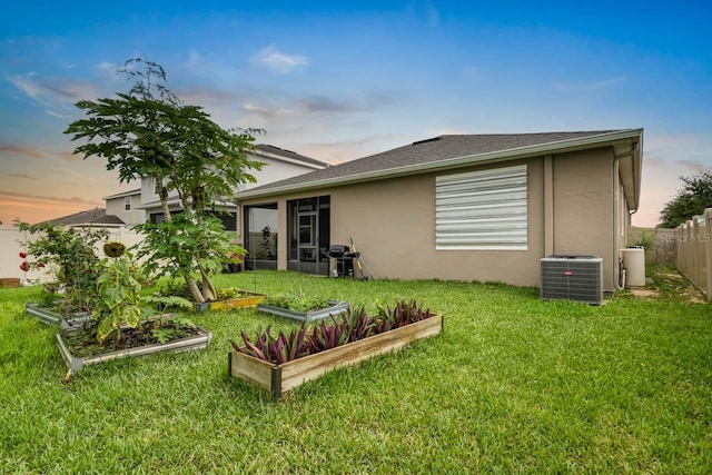 5006 Jackel Chase Dr, Wimauma, FL 33598 - back of house at dusk with central AC, a garden, and stucco siding