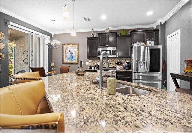 3901 Silverlake Way, Wesley Chapel, FL 33544 - kitchen featuring stainless steel appliances, ornamental molding, a chandelier, light stone counters, and tasteful backsplash