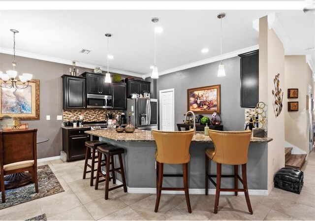 3901 Silverlake Way, Wesley Chapel, FL 33544 - kitchen with appliances with stainless steel finishes, dark cabinetry, a kitchen breakfast bar, a chandelier, and decorative backsplash
