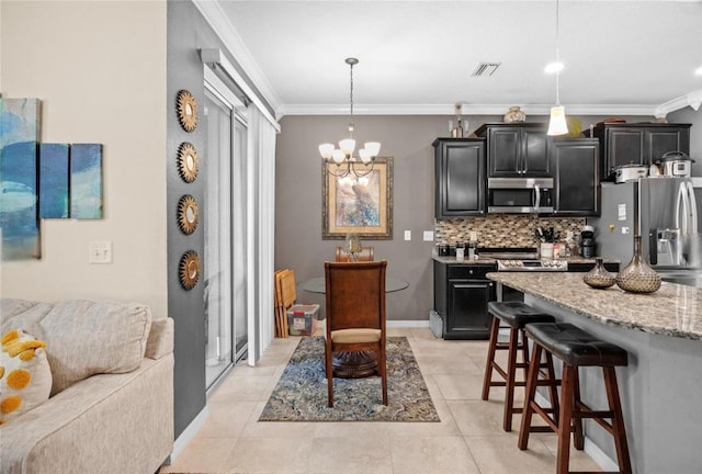 3901 Silverlake Way, Wesley Chapel, FL 33544 - kitchen featuring appliances with stainless steel finishes, crown molding, a kitchen breakfast bar, dark cabinetry, and a chandelier
