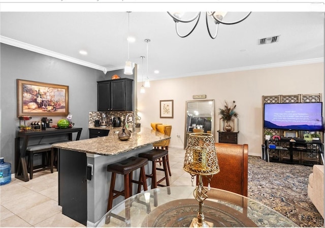 3901 Silverlake Way, Wesley Chapel, FL 33544 - kitchen featuring a kitchen breakfast bar, crown molding, light tile patterned flooring, light stone countertops, and dark cabinetry