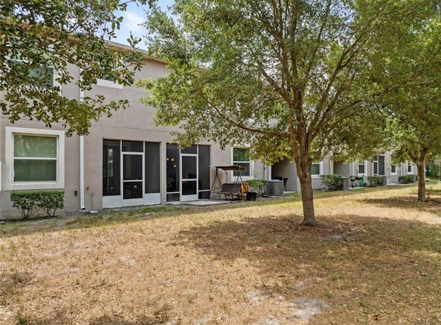 3901 Silverlake Way, Wesley Chapel, FL 33544 - back of house featuring central air condition unit, stucco siding, a yard, and a sunroom