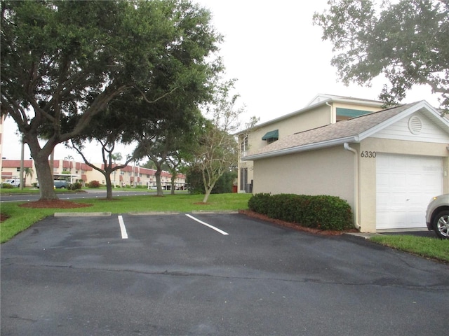 6330 99th Way N Unit 14B, Seminole, FL 33708 - view of side of home with stucco siding, uncovered parking, and a lawn