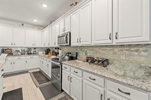 944 Old Windsor Way, Spring Hill, FL 34609 - kitchen featuring appliances with stainless steel finishes, white cabinets, decorative backsplash, recessed lighting, and light stone countertops